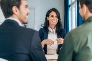 Female professional across desk from 2 other professionals