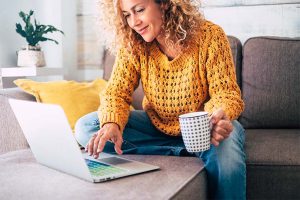 Woman looking at her laptop while holding a mug